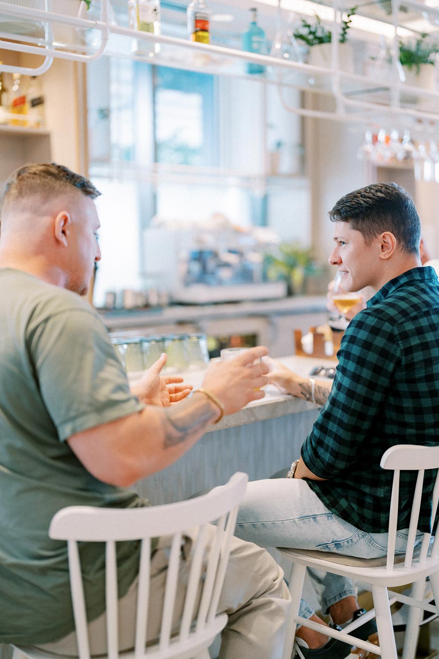 Two people having a conversation at a cafe counter with a modern interior, emphasizing social interaction and a casual atmosphere.