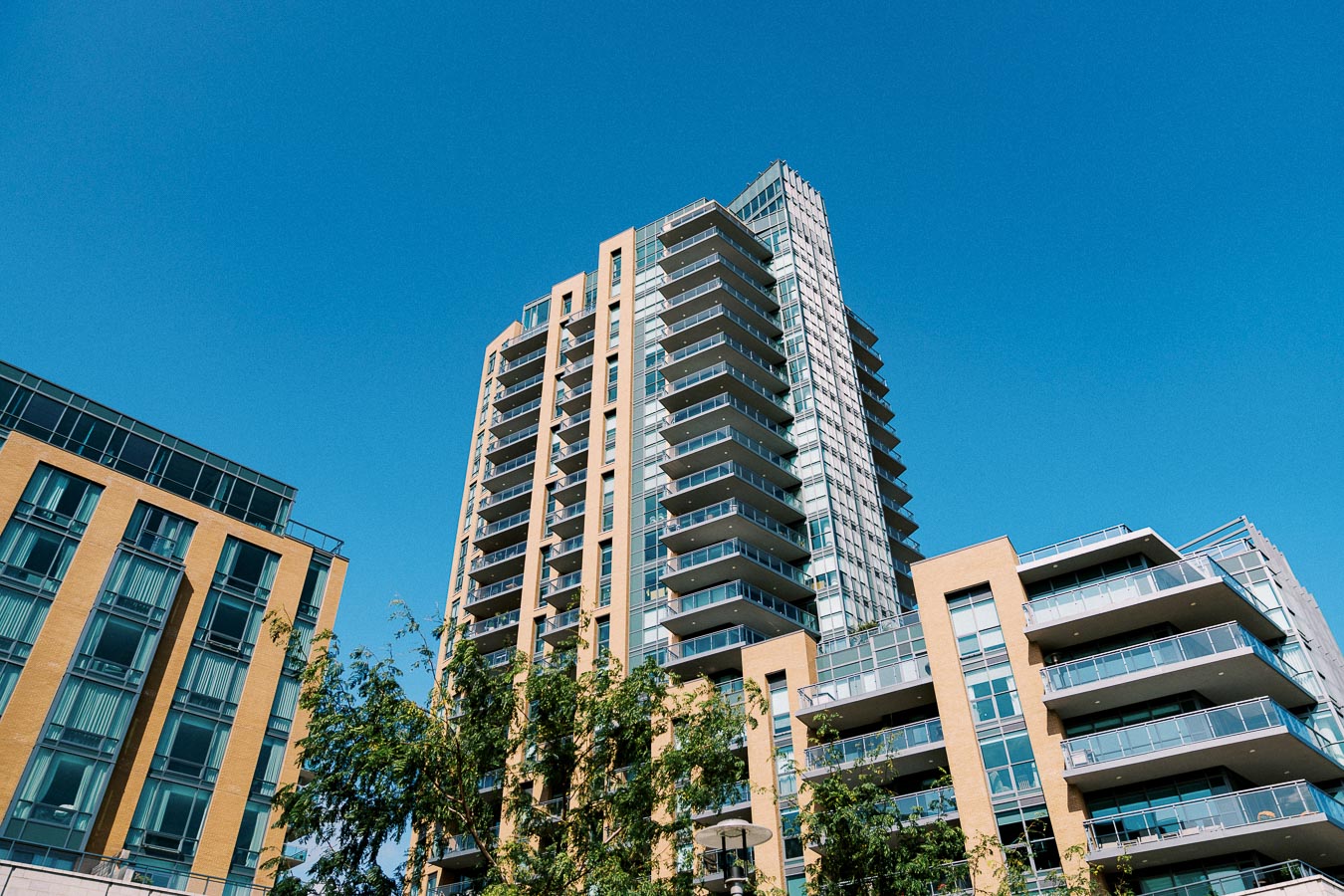 Modern high-rise apartment building with balconies against a clear blue sky.