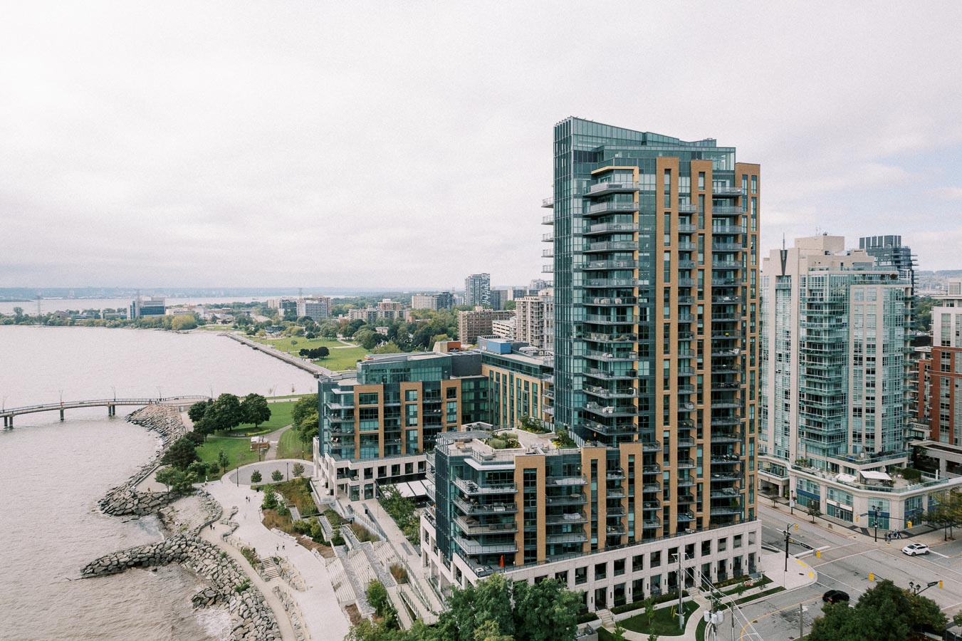 Aerial view of modern high-rise buildings and waterfront park in an urban cityscape, showcasing the blend of architecture and natural scenery along the shoreline.