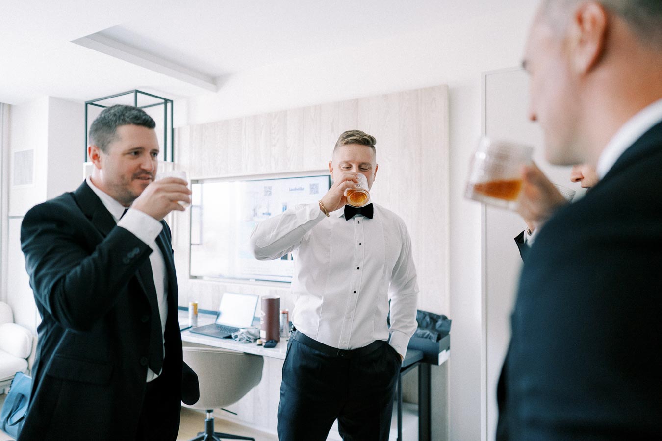 Men in formal attire enjoying drinks together in a modern room.