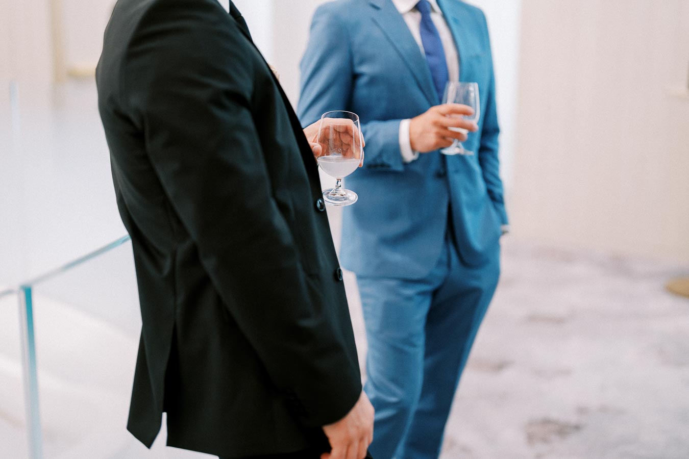 Business professionals in suits holding drinks at a formal networking event, highlighting corporate interaction and social engagement.