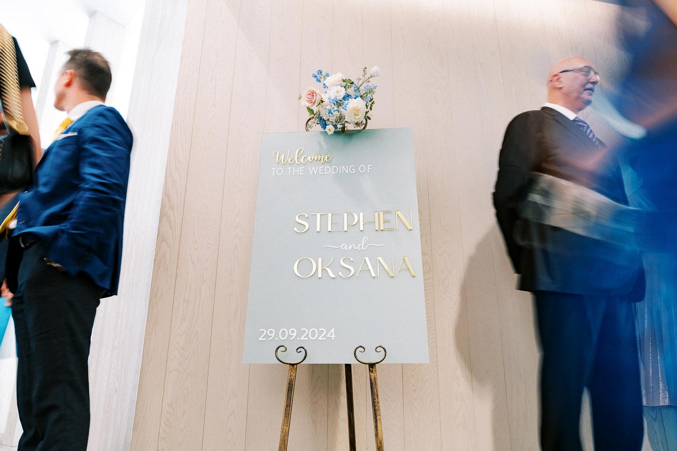 Wedding welcome sign for Stephen and Oksana dated September 29, 2024, with floral decoration on top, placed on an easel at a wedding venue entrance.