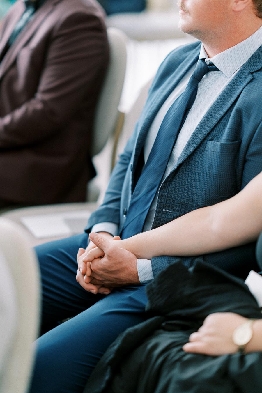 A man in a blue suit holds hands with a woman during a formal event, highlighting a moment of connection and support.