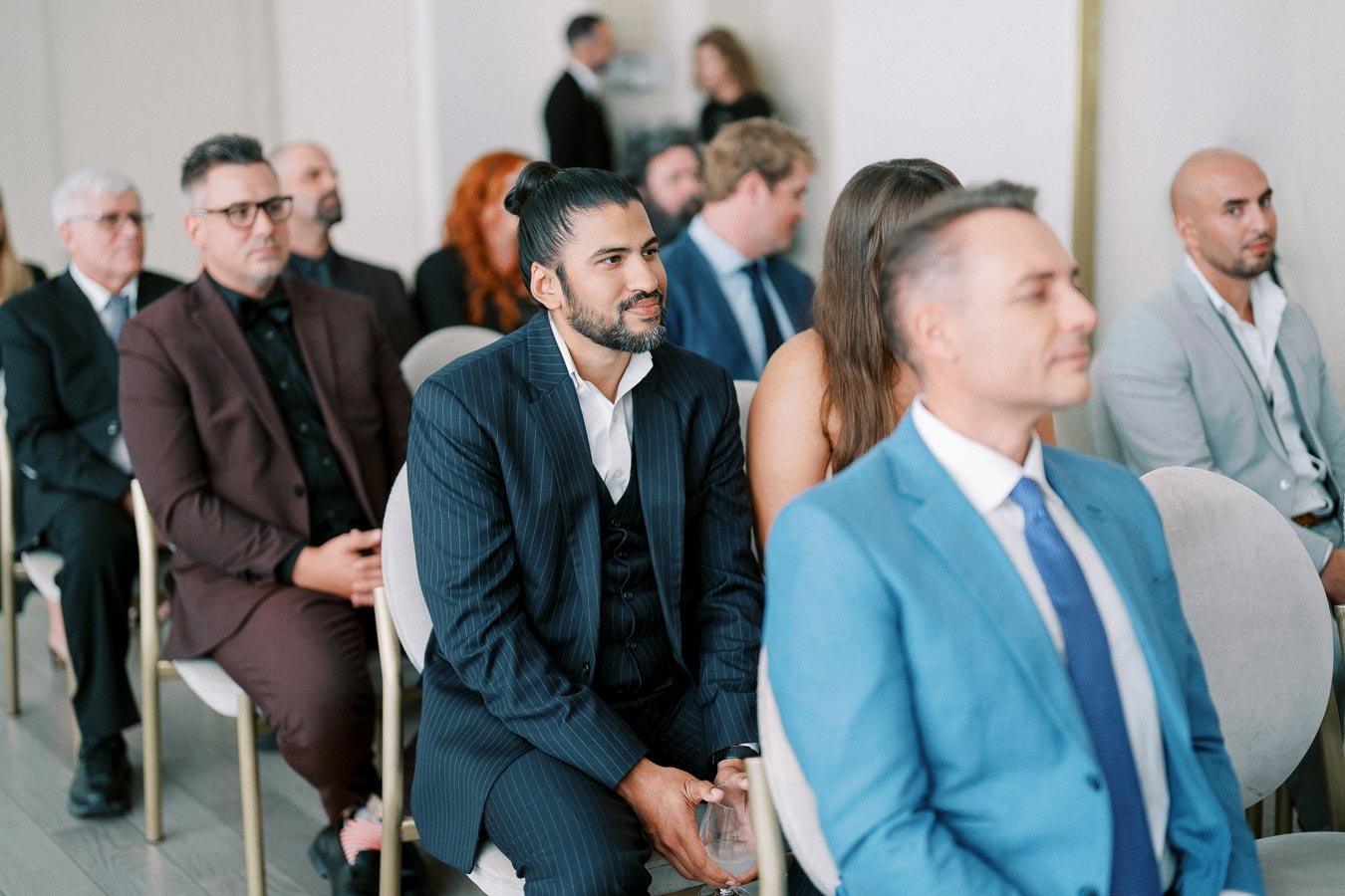 A diverse group of professionally dressed individuals attentively seated in a conference or seminar setting.