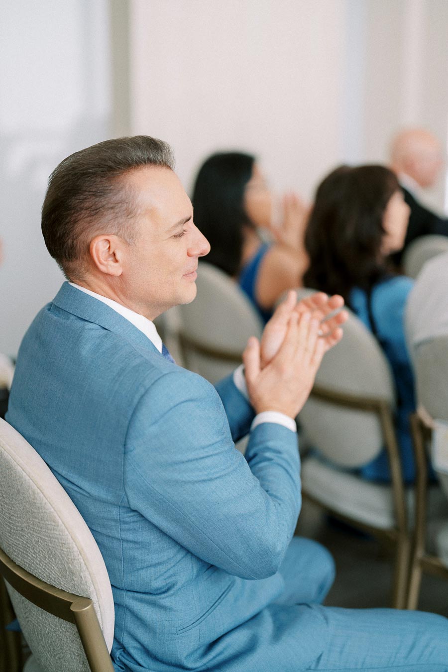 Male professional in a blue suit applauding at a business conference.