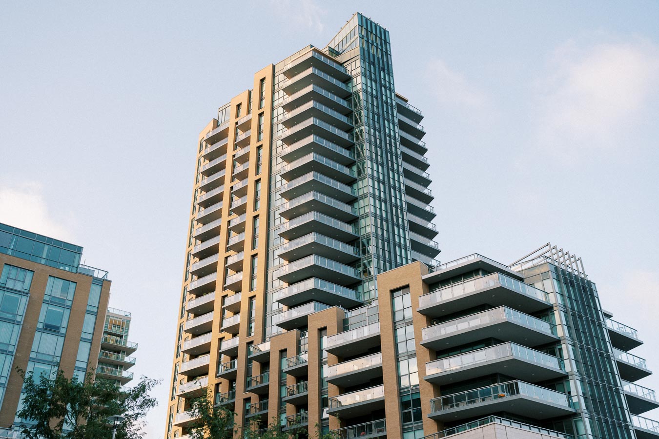 High-rise modern apartment building with glass balconies under a clear blue sky.