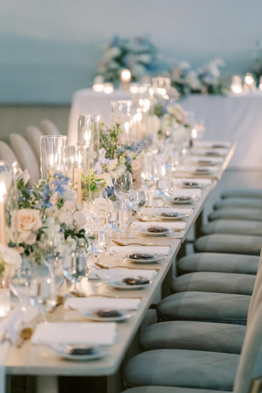Elegant wedding table setting with candles and floral centerpieces, featuring pastel roses and greenery, creating a romantic and luxurious ambiance.