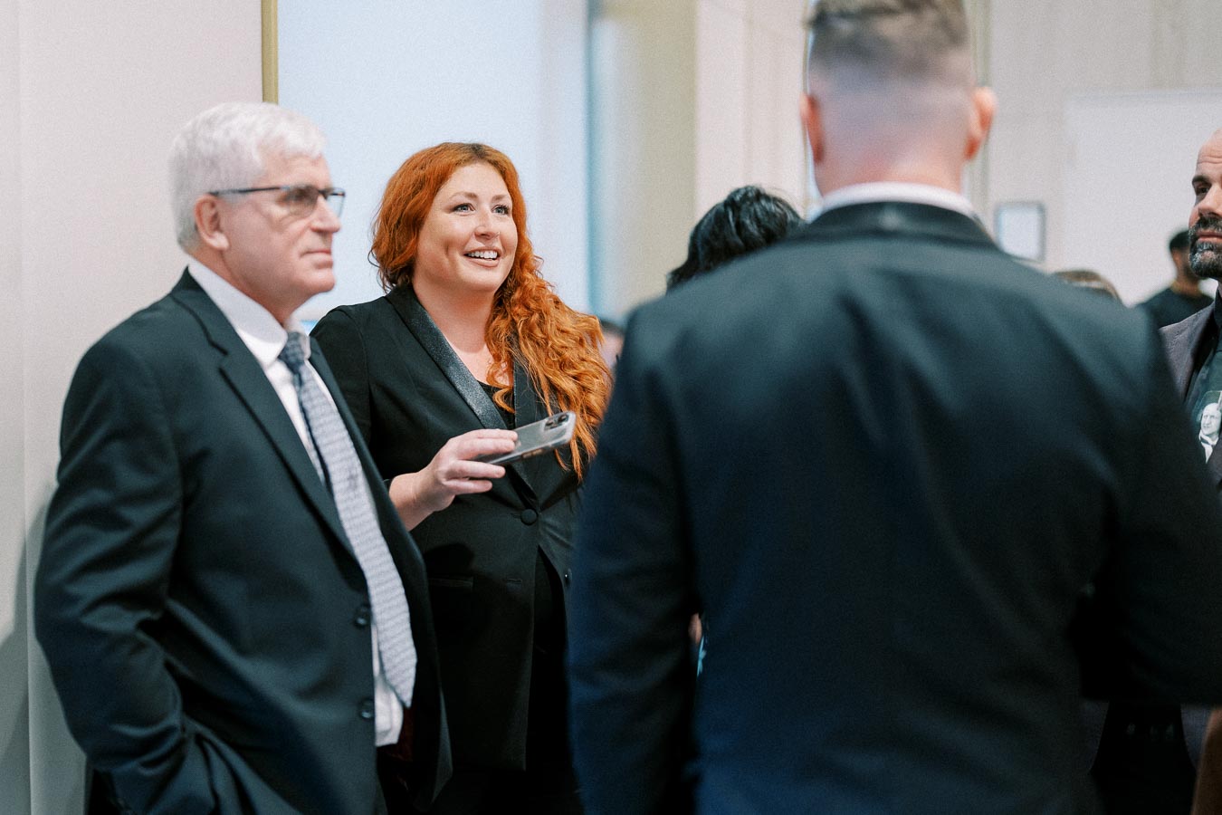 Business professionals networking at a corporate event, engaging in conversation while wearing formal attire.