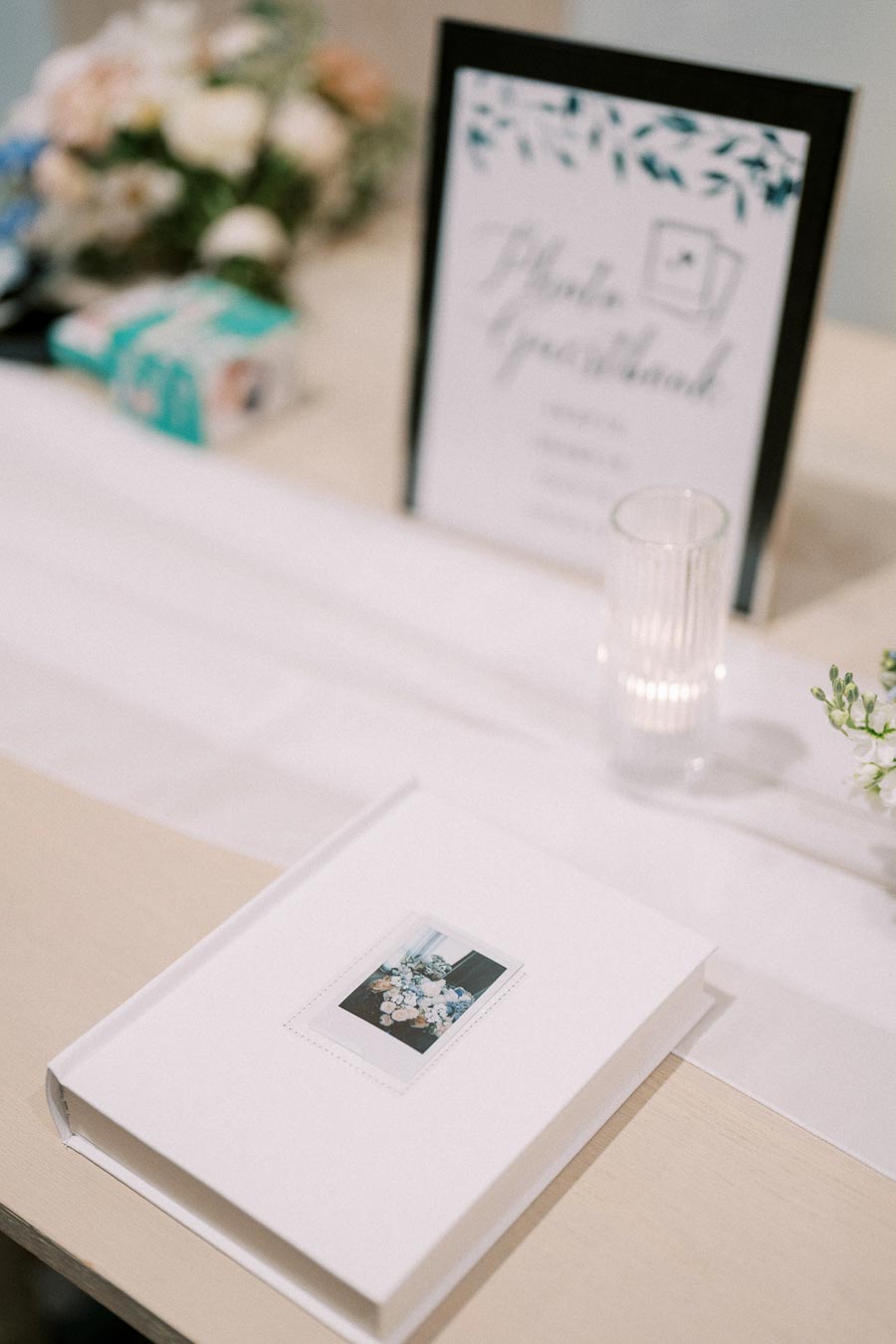 Wedding guest book table featuring a Polaroid guest book, a printed sign, and floral decorations, highlighting an elegant, modern wedding reception setup.