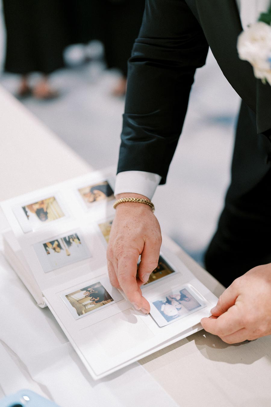 Person in a suit arranging instant photos in a photo album at an event.