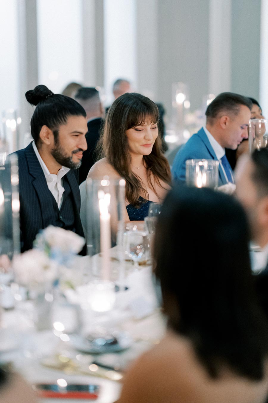 Elegant dinner event with guests seated at a beautifully set table adorned with candles and floral arrangements.