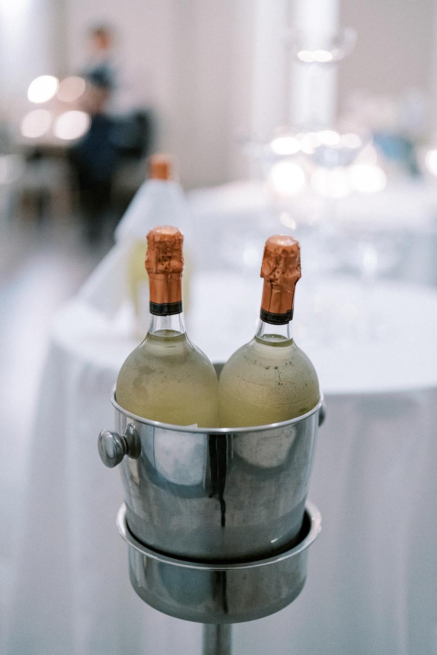 Two chilled champagne bottles in a silver ice bucket at an elegant event setting