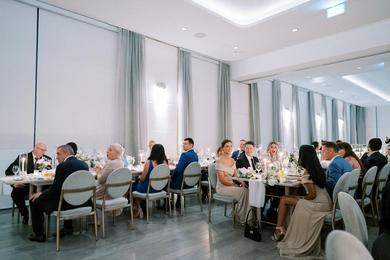 Elegant wedding reception with guests seated at beautifully decorated tables, enjoying a sophisticated indoor dining experience.