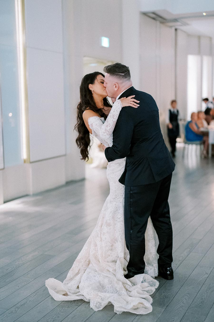 A bride and groom share a romantic kiss during their first dance at a wedding reception.