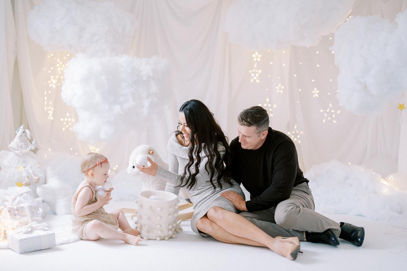 Family playing together in a whimsical winter-themed setting with fluffy clouds and twinkling lights, creating a cozy and festive atmosphere.