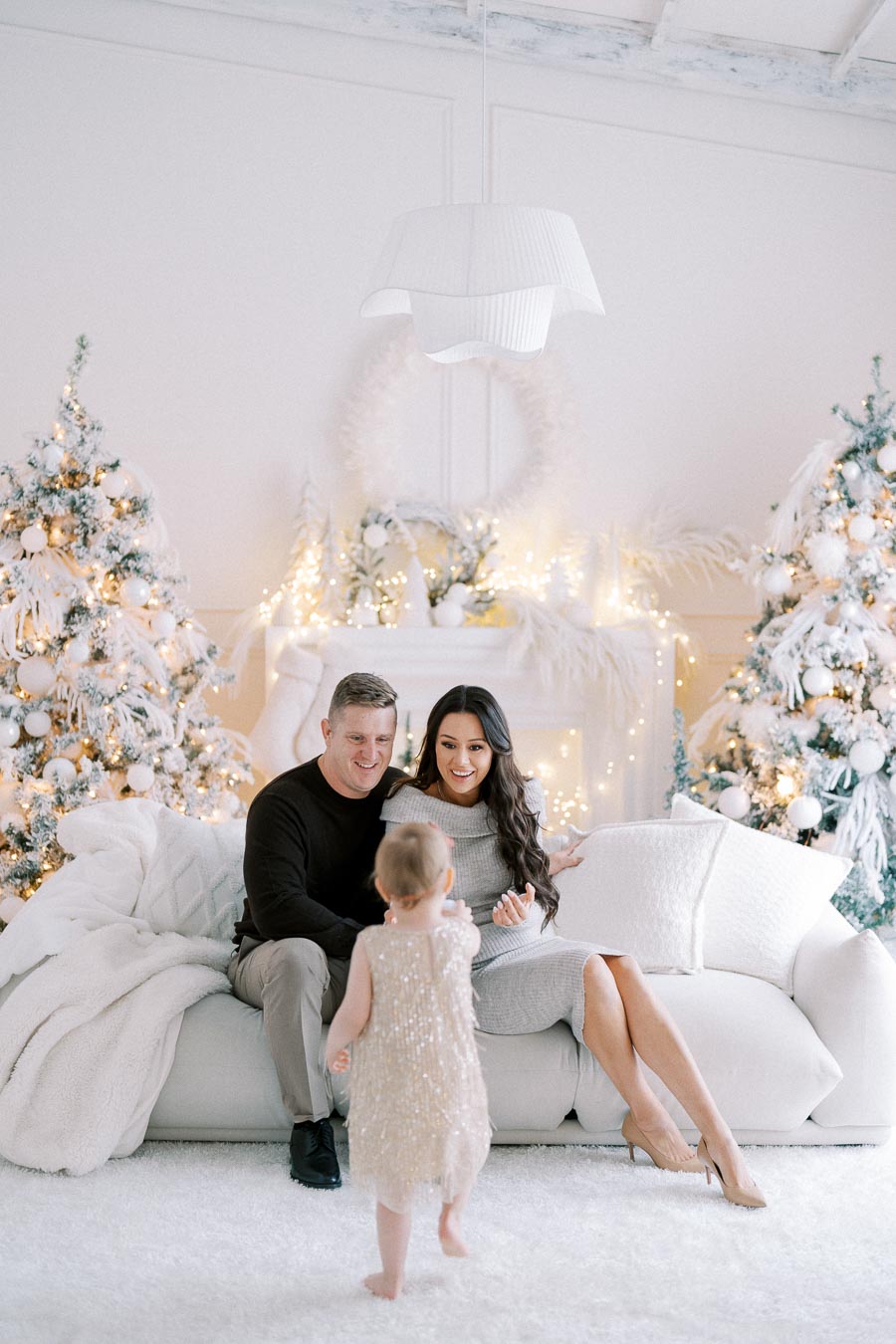 Happy family enjoying a festive moment together in a beautifully decorated living room with Christmas trees and lights.
