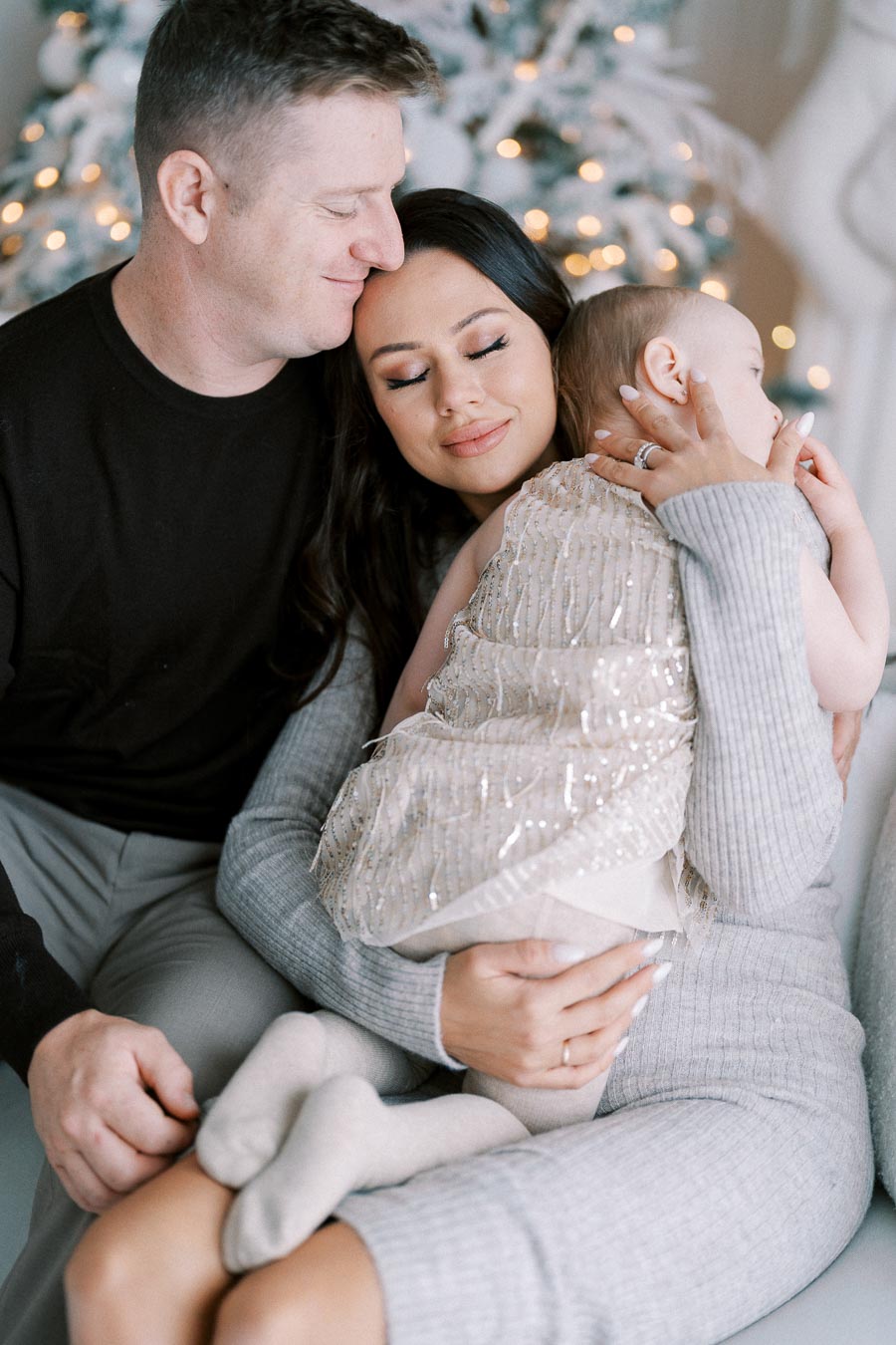 Family enjoying a tender moment together in front of a decorated Christmas tree, capturing the warmth and love of the holiday season.