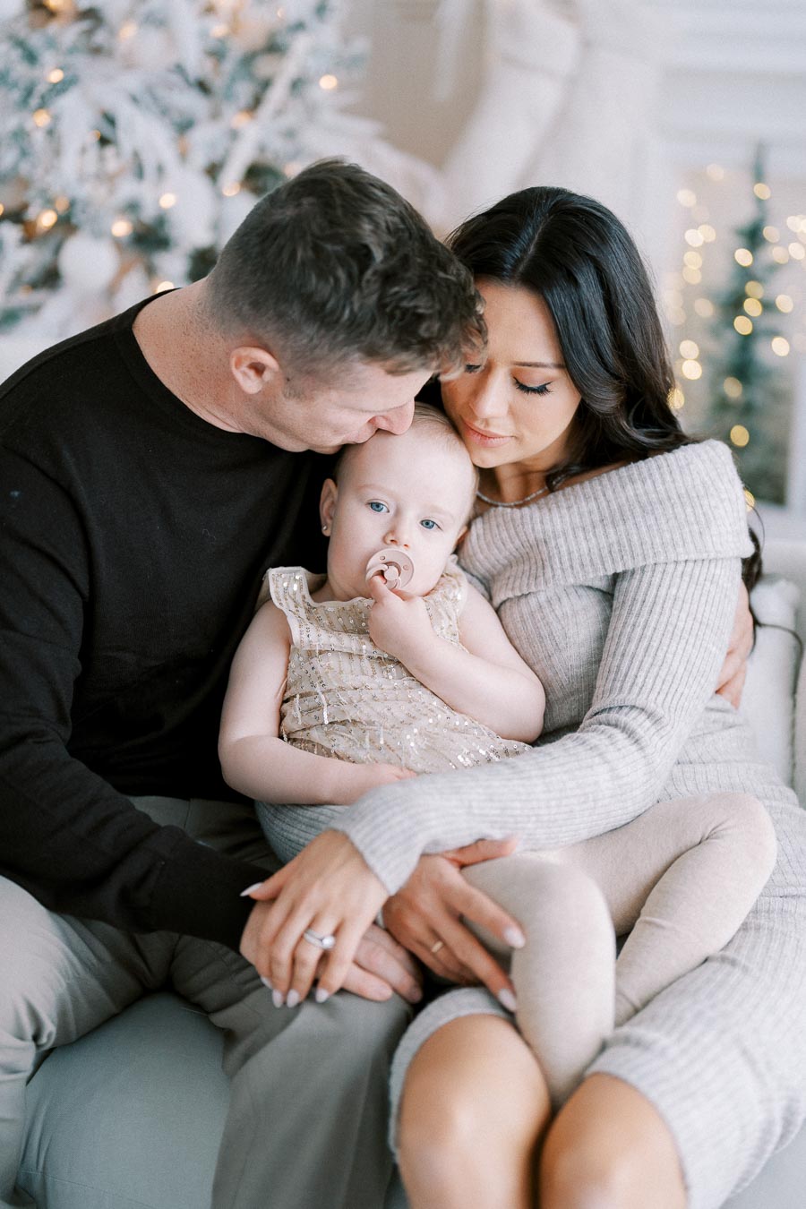 A loving family cuddles on a cozy sofa with a decorated Christmas tree in the background, capturing the warmth and joy of the holiday season.