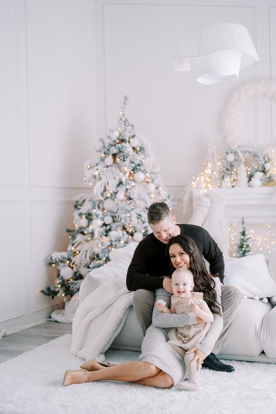 Family sitting together in a cozy living room adorned with a beautifully decorated Christmas tree in the background and warm holiday lights, creating a festive atmosphere.