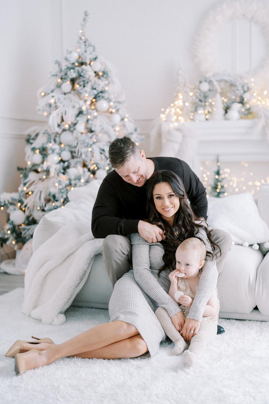 Family posing together in front of a decorated Christmas tree, with a cozy holiday ambiance.