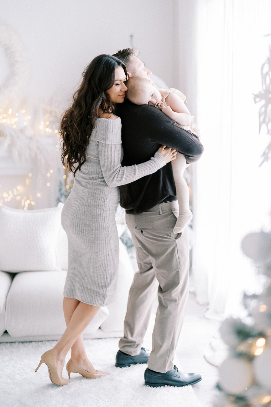 A loving family embracing in a cozy, light-filled living room adorned with festive holiday decorations, creating a warm and joyful atmosphere.