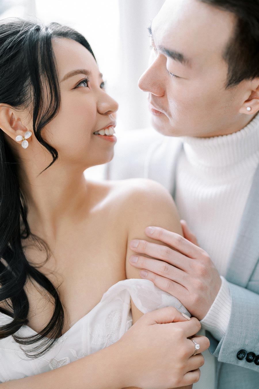 Happy couple gazing at each other in a romantic embrace, highlighting engagement or wedding moments.