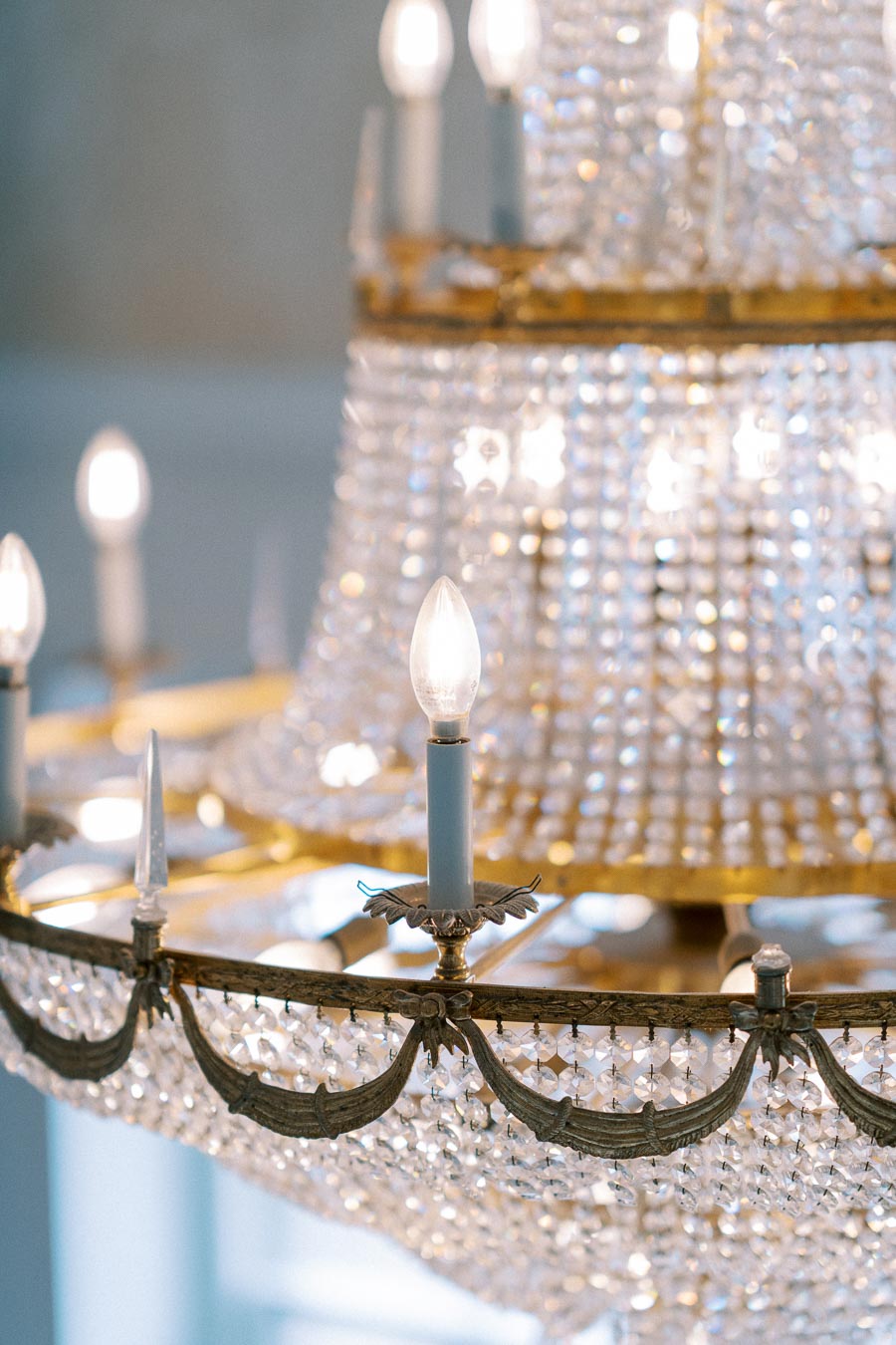 Elegant crystal chandelier with glowing candle-shaped bulbs, featuring intricate metalwork and cascading glass pendants, creating a luxurious ambiance.