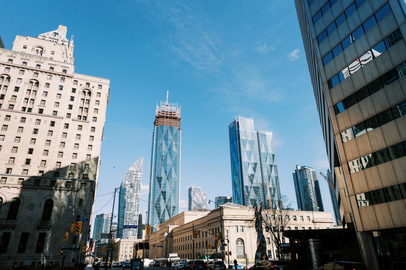 A vibrant cityscape showcasing a mix of modern skyscrapers and historic architecture under a clear blue sky.