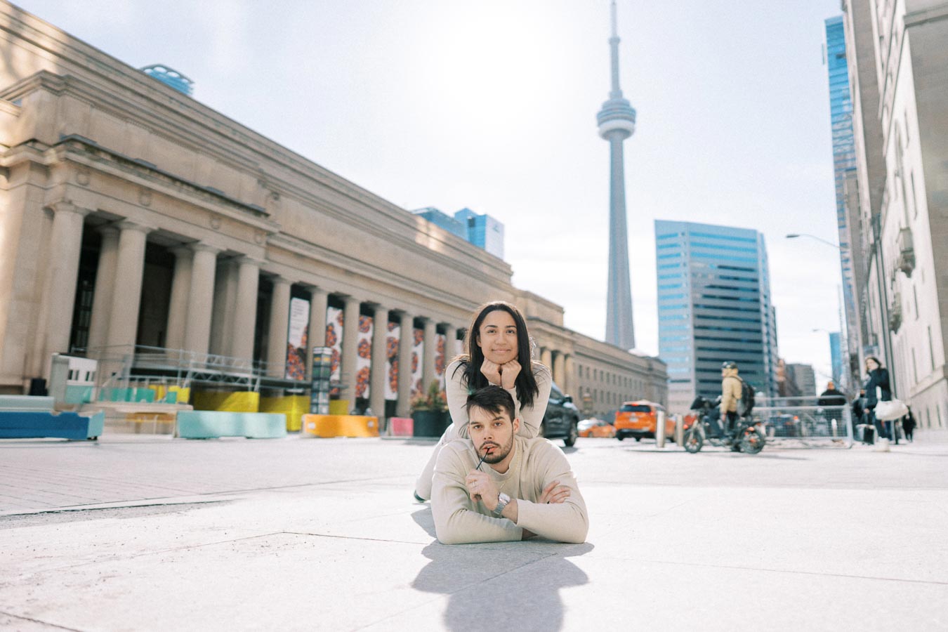 A couple poses playfully in front of Union Station with the CN Tower in the background in Toronto.