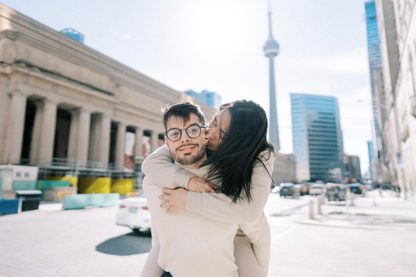 A joyful couple shares a moment in Toronto, with the iconic CN Tower in the background.