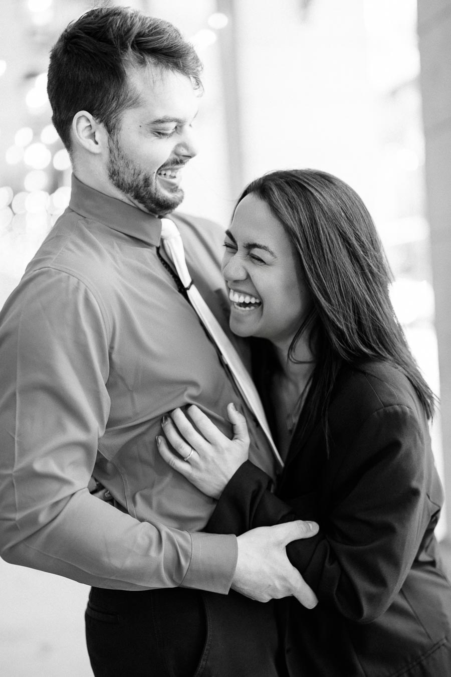A joyful couple shares a laugh in a black and white photograph, capturing a moment of happiness and connection.