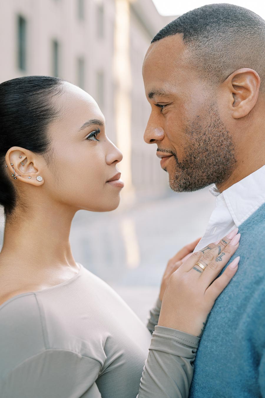 A couple shares an intimate moment, gazing into each other's eyes outdoors.