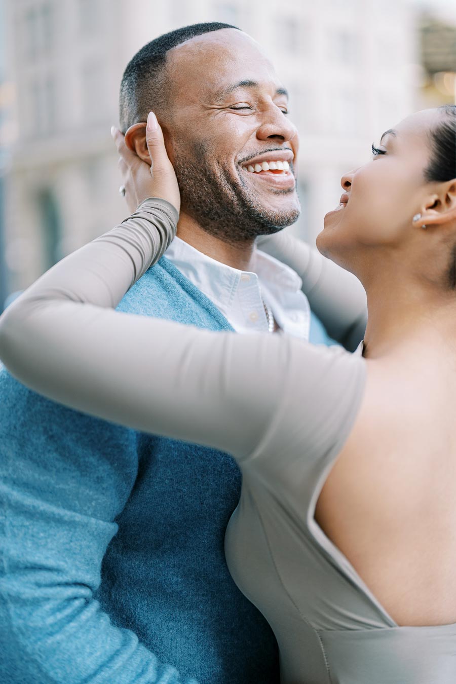 A joyful couple shares a tender moment, smiling and embracing each other outdoors.