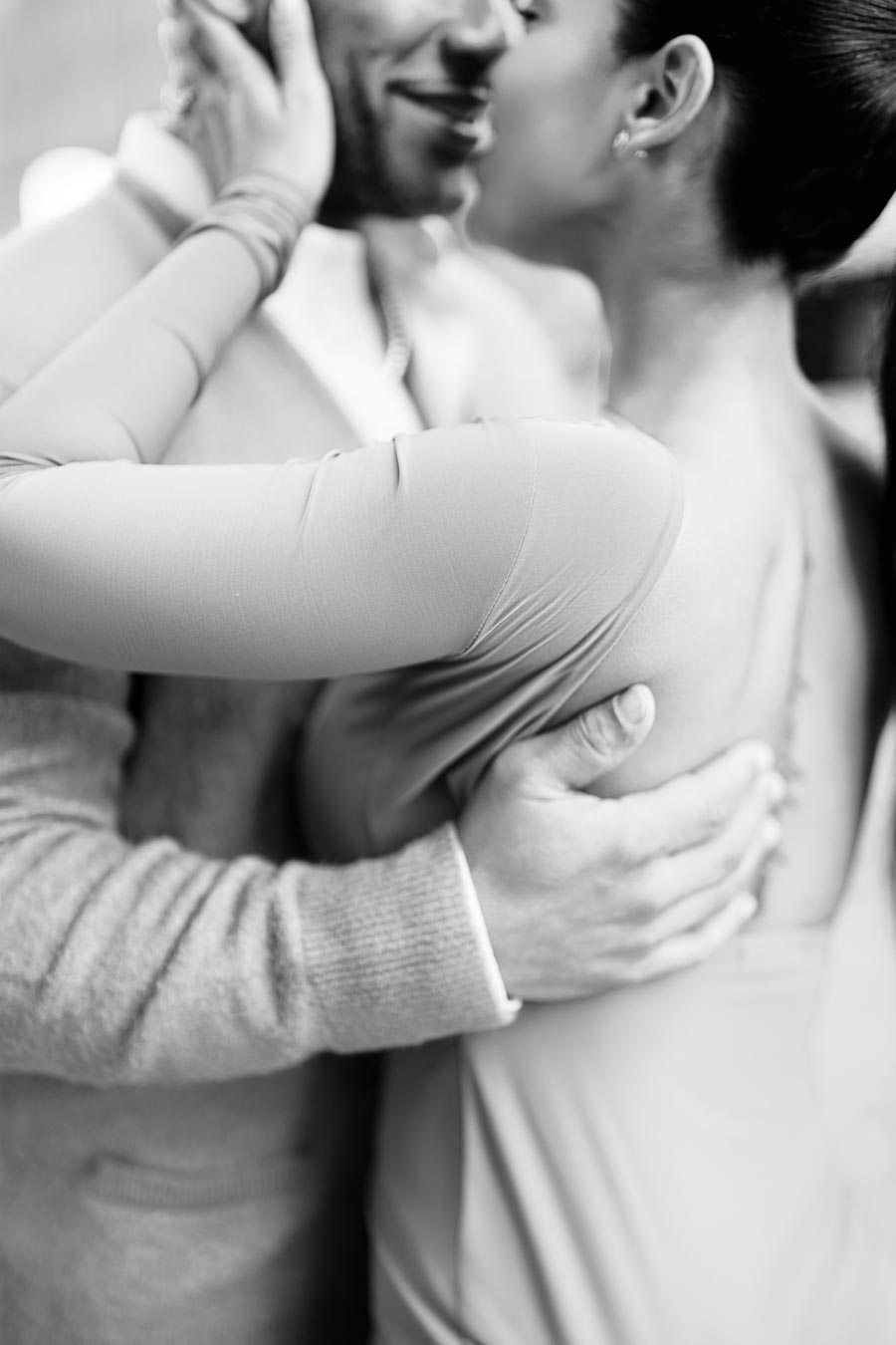 A black and white image capturing an intimate moment between a couple, highlighting their embrace and gentle touch.