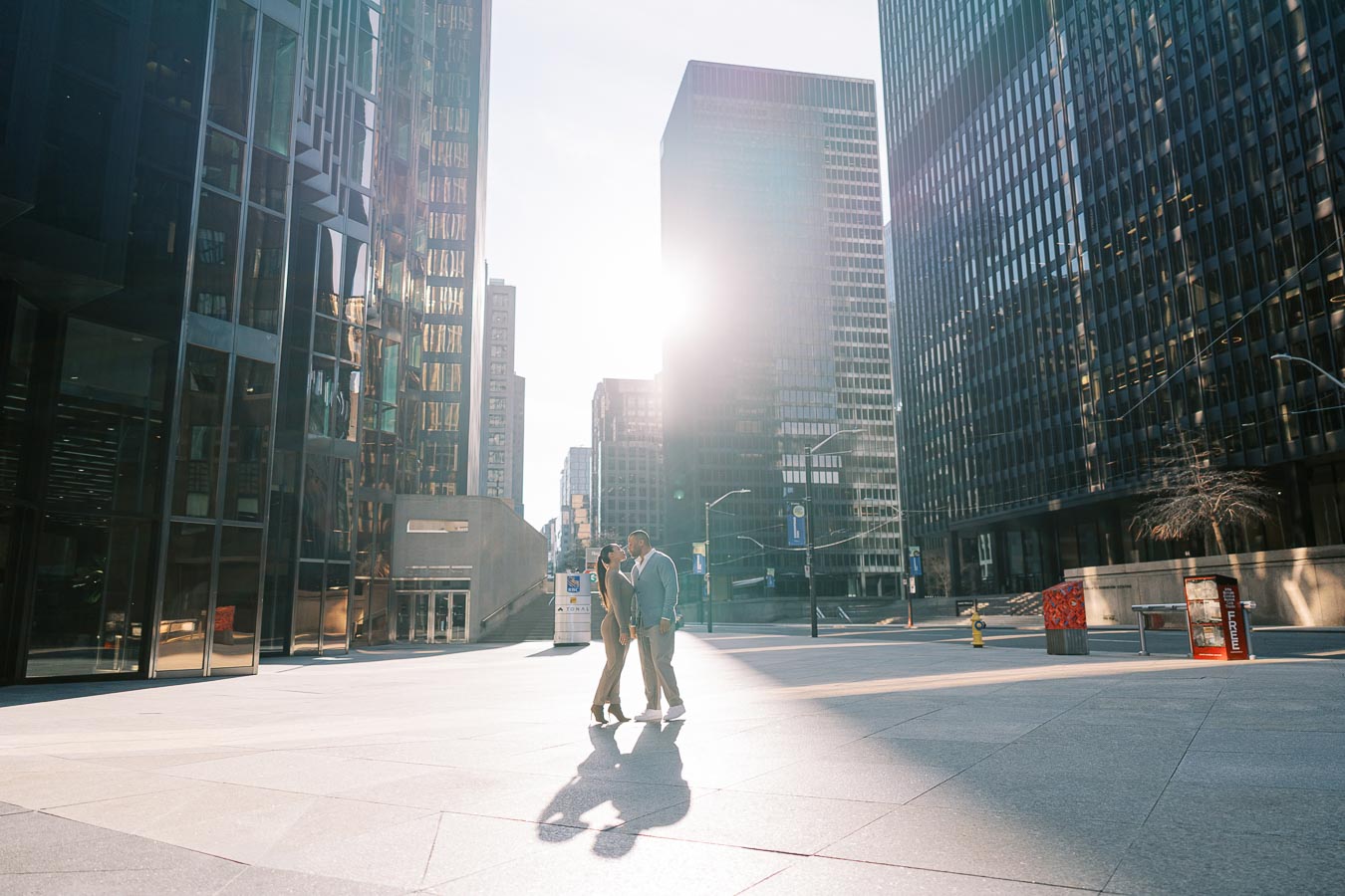 Wide-angle shot of DeVon Franklin and Maria Castillo in downtown Toronto surrounded by skyscrapers during engagement session