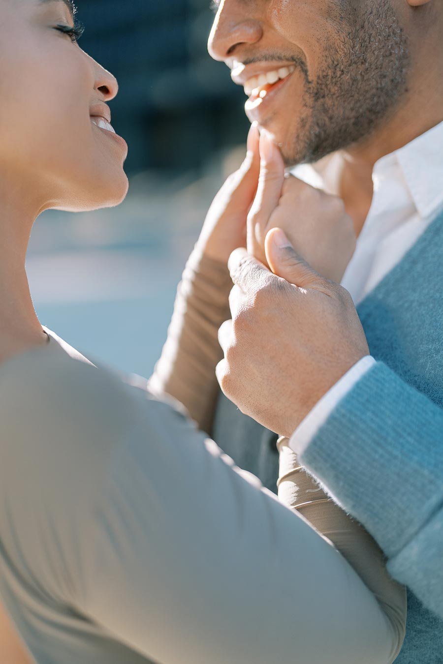 A close-up shot of a couple sharing a tender moment, smiling and gently touching each other's faces.