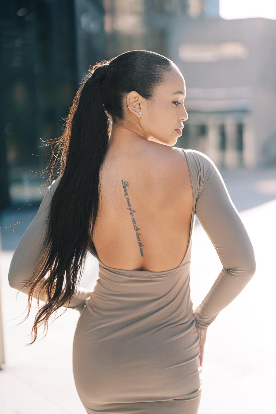 Maria Castillo with long hair and back tattoo in open-back dress during engagement photoshoot in downtown Toronto