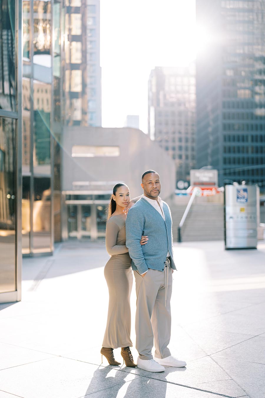 DeVon Franklin and Maria Castillo standing together in front of Toronto skyscrapers during an elegant engagement session