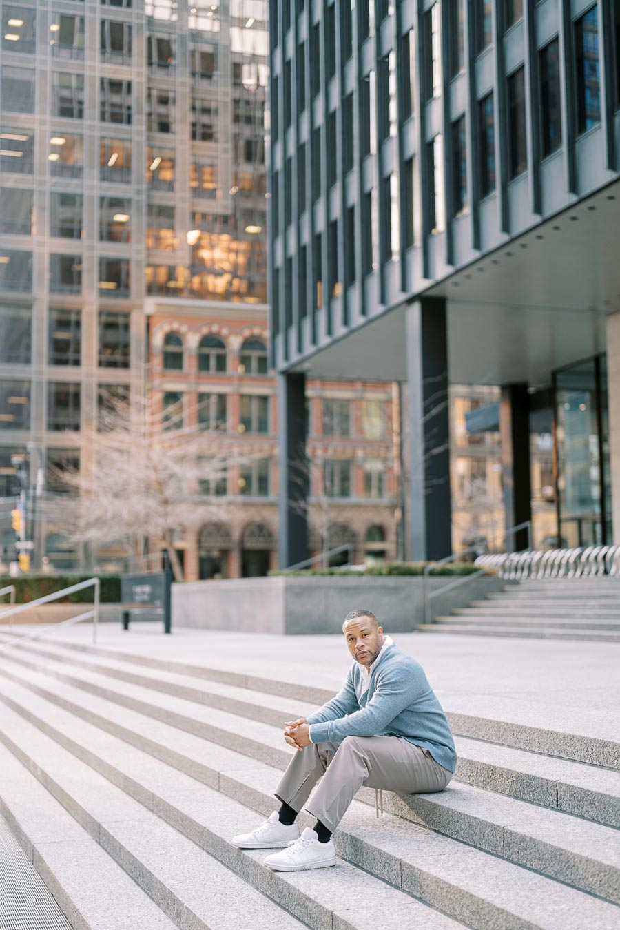 Man sitting alone on granite steps in downtown Toronto during engagement photoshoot