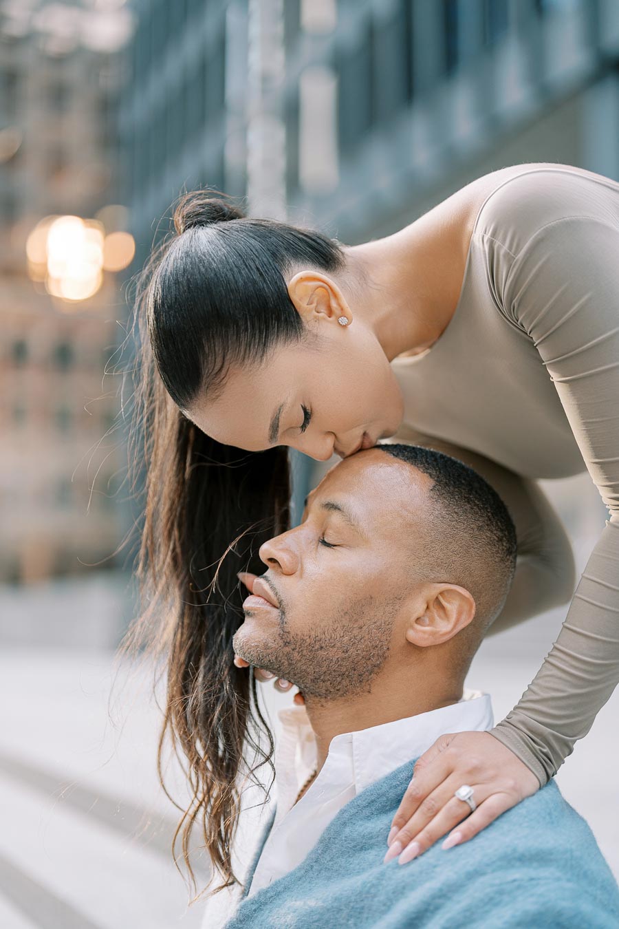 Woman kissing man’s forehead in quiet moment during downtown Toronto engagement shoot