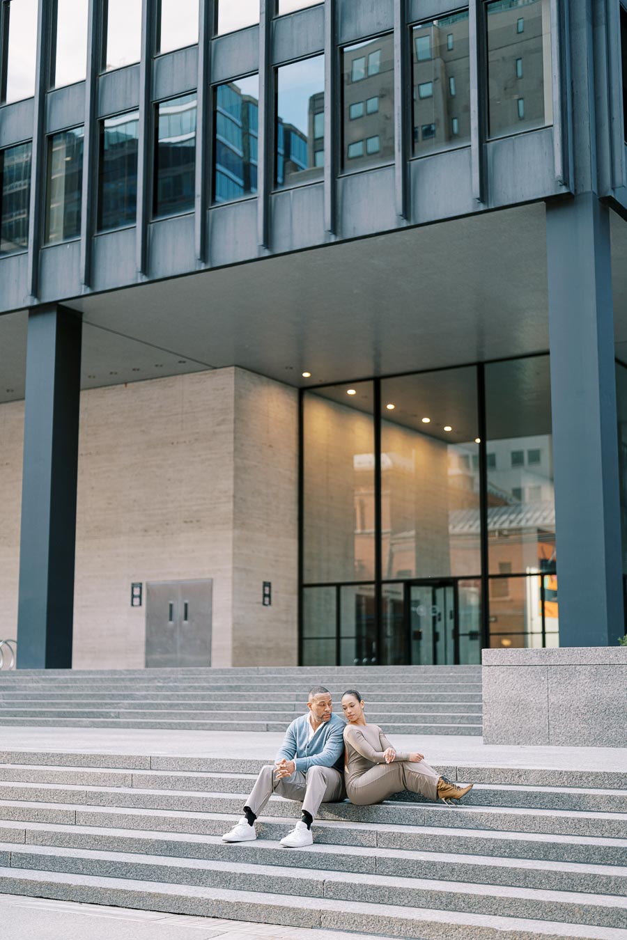 Couple sitting on large architectural steps during downtown Toronto engagement photoshoot