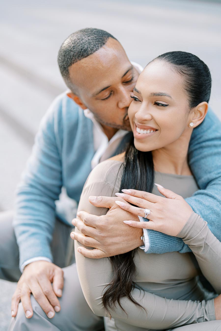 Groom-to-be kissing smiling fiancée as she shows engagement ring during downtown Toronto engagement shoot