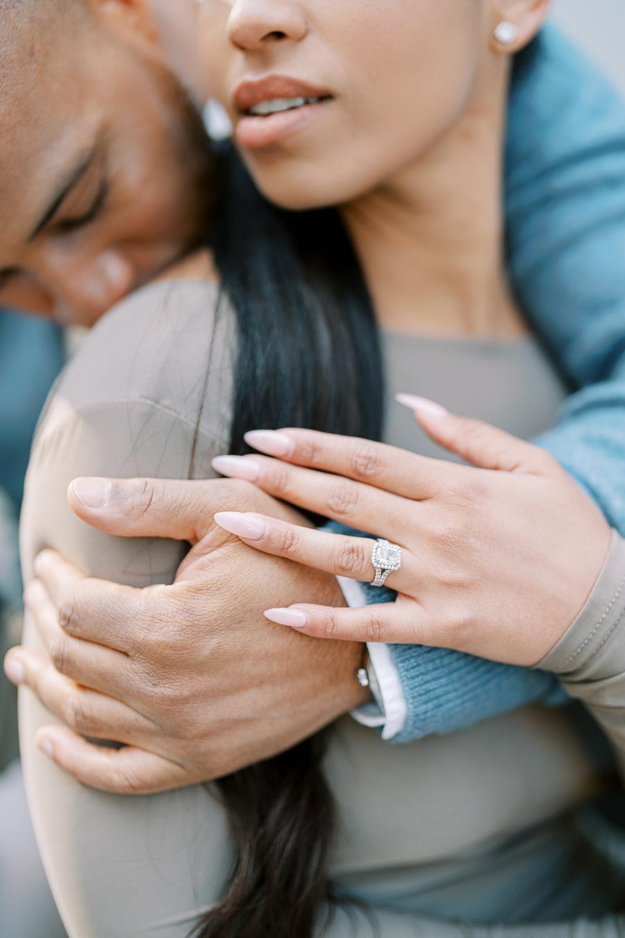 Close-up of engagement ring on bride-to-be’s hand as groom embraces her during Toronto photoshoot