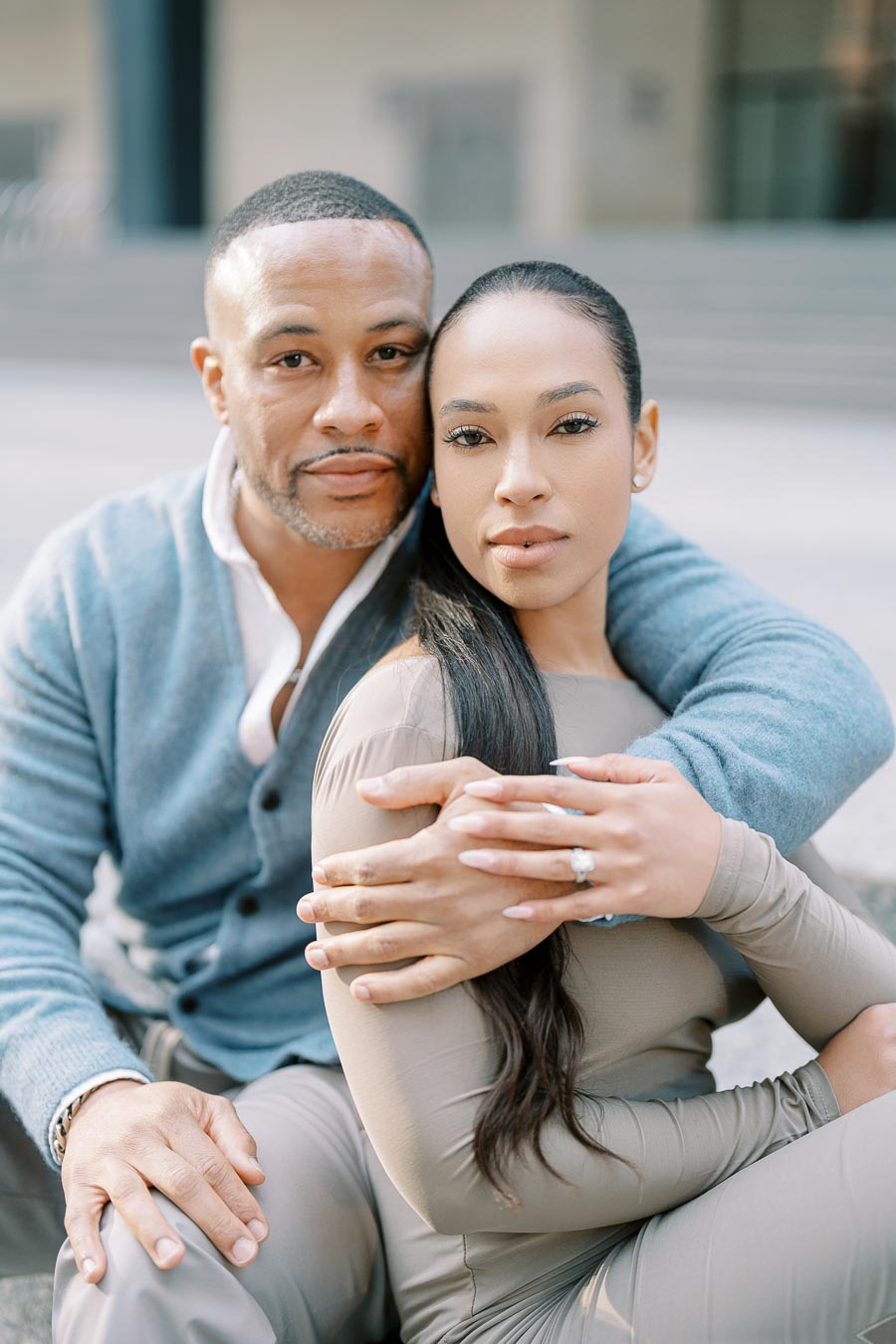 Engaged couple sitting closely with serious expressions during stylish downtown Toronto photoshoot