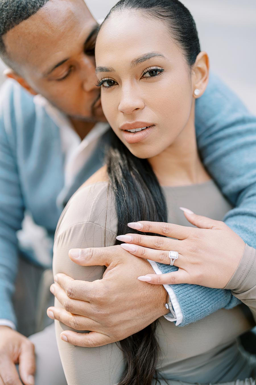 Fiancée showing her engagement ring while embraced by her partner during downtown Toronto photoshoot