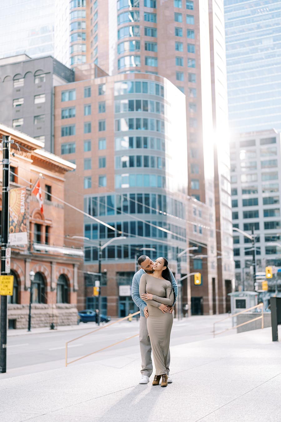 Couple standing on sunlit downtown Toronto street sharing an intimate moment during engagement photoshoot