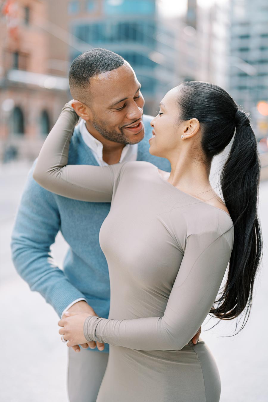 Couple smiling and leaning in for a kiss during playful engagement photoshoot in downtown Toronto