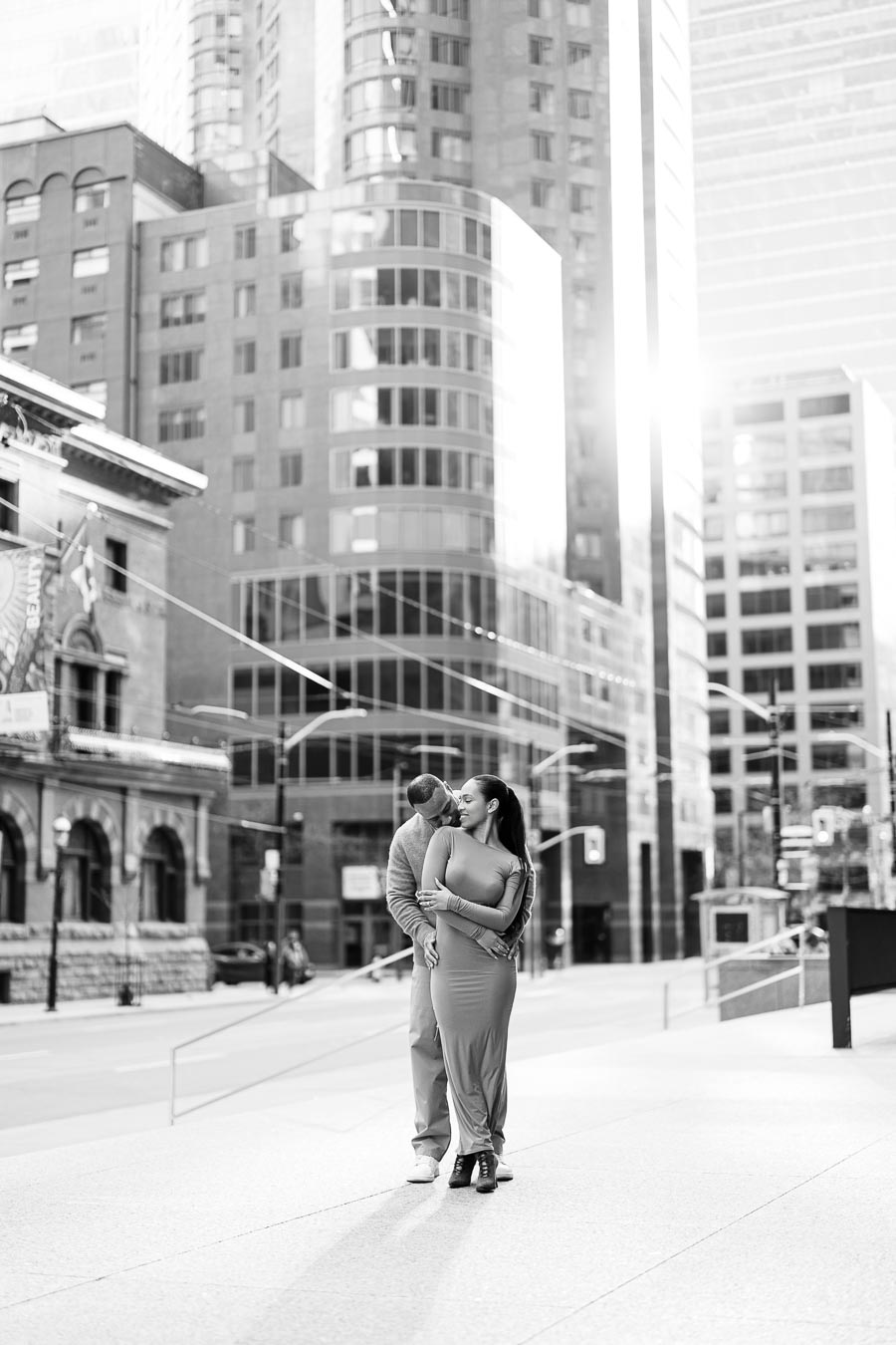 Couple standing on empty downtown Toronto street surrounded by modern skyscrapers during engagement photoshoot