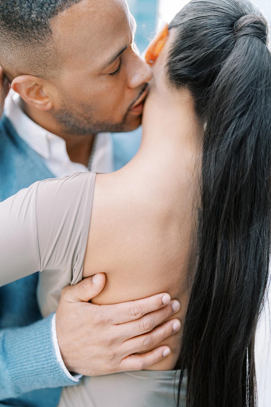 A tender moment between a couple as the man kisses the woman's neck, showcasing intimacy and affection.