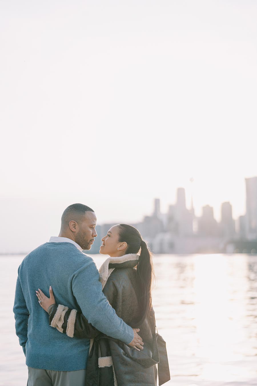 Couple looking at each other during Toronto engagement session at sunset by the water